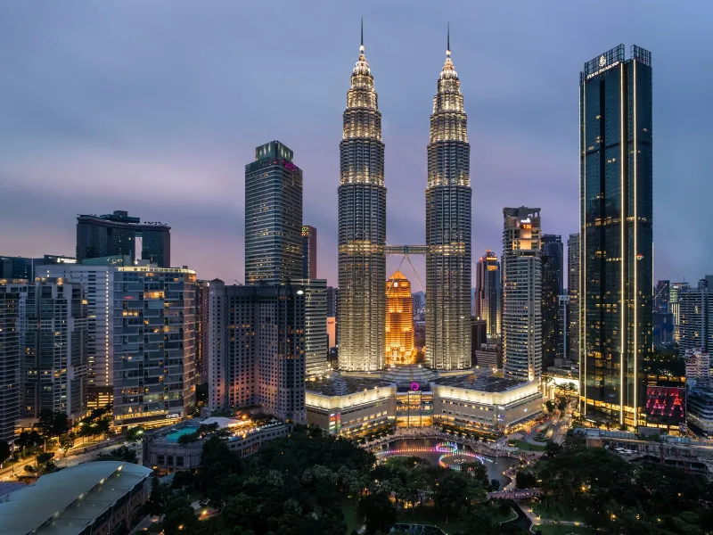 Les tours jumelles Petronas illuminées au crépuscule au-dessus de la skyline de Kuala Lumpur