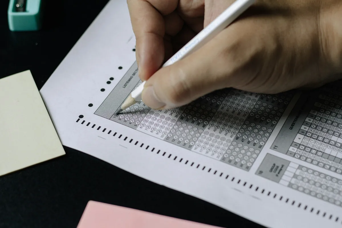 Main remplissant au crayon une grille de réponses d'examen à choix multiples