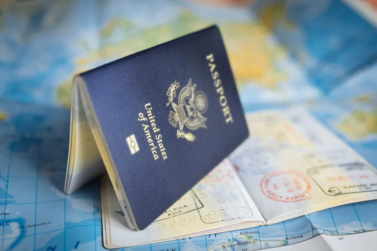 Passeport posé sur une carte du monde, à côté de pages portant des tampons de visa